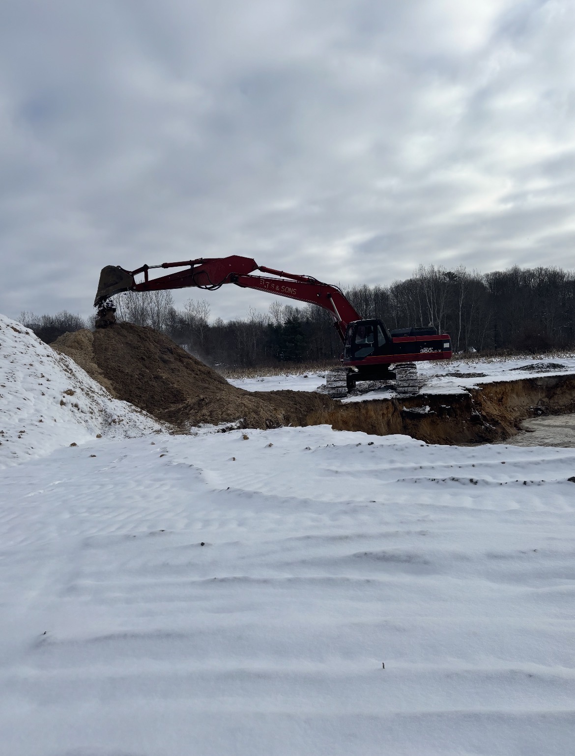 Excavator digging a pond in winter conditions
